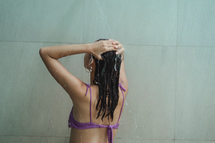 Mulher tomando banho usando pré-shampoo